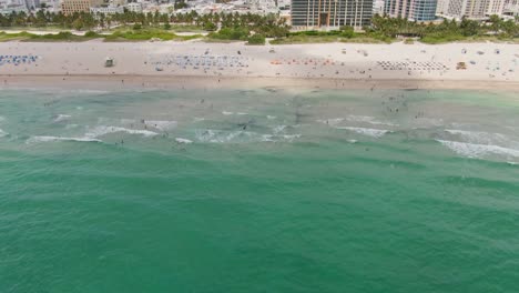 Crystal-clear-Atlantic-ocean-and-reveal-of-Miami-skyline,-aerial-tilt-up-view