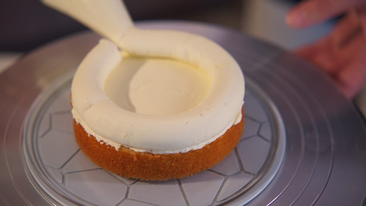 Primo piano di uno chef che decora una torta rotonda con glassa bianca