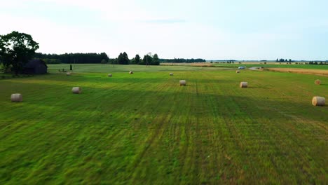 Fliegen-Sie-Schnell-über-Die-Grüne-Landschaft-Mit-Verstreuten-Heuballen-Auf-Dem-Ackerland