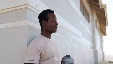 Black-man,-drinking-water-and-relax-in-fitness