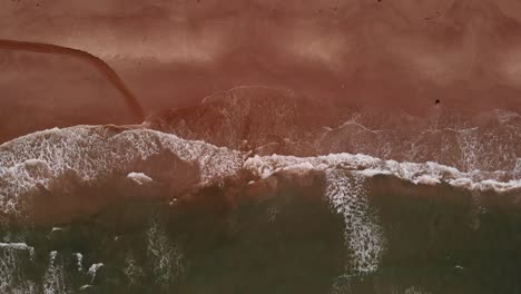 4k aerial of empty sand beach with wide waves while slowly moving closer to the shoreline