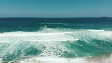 drone aéreo moviéndose rápido mostrando interminables olas salvajes rompiendo en la costa arenosa
