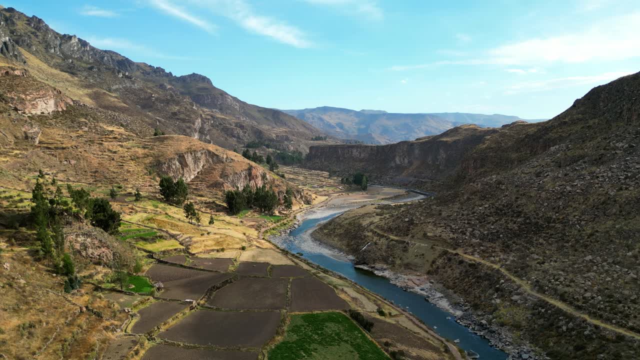 4K cinematic drone reveal of golden fields along a twisting river beneath towering Andean peaks, captured in crisp morning light
