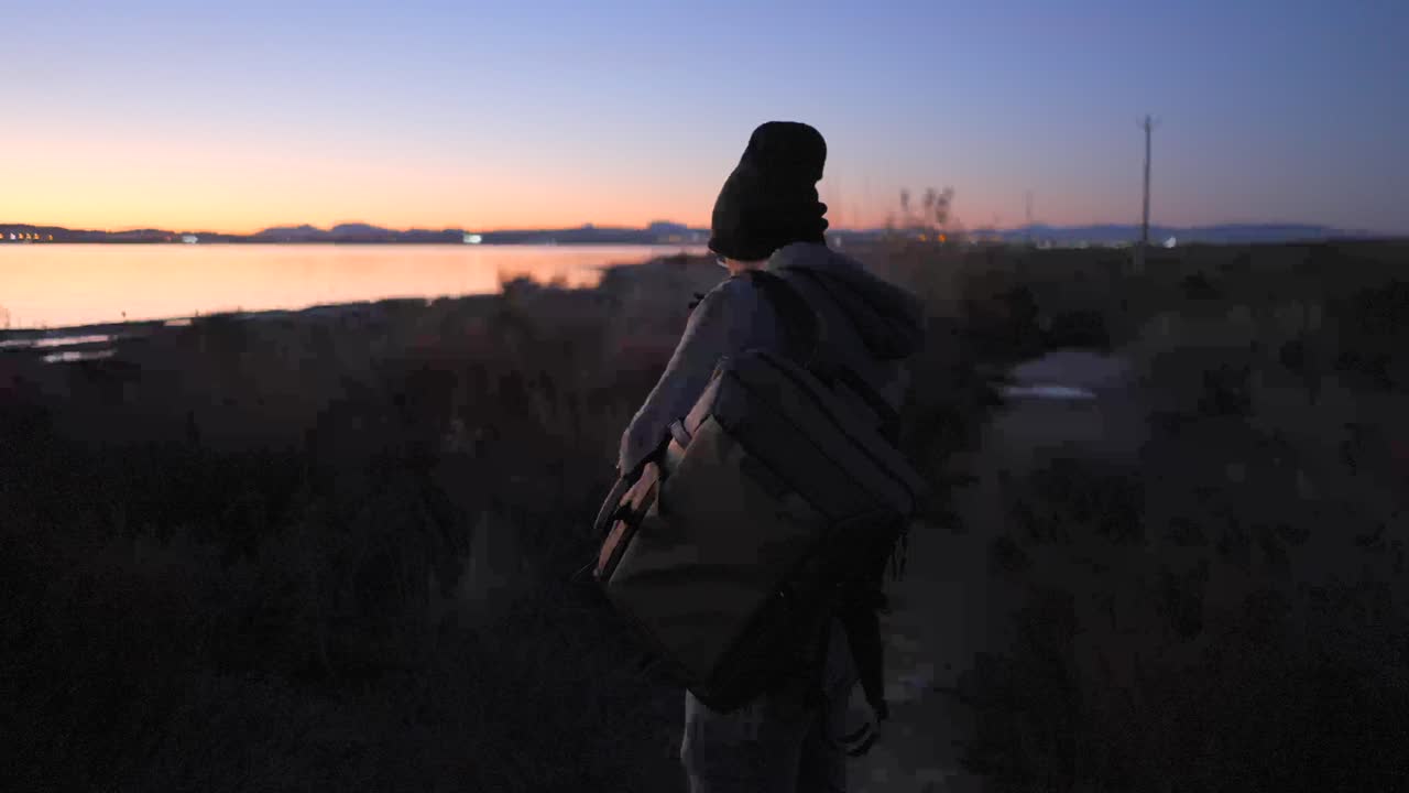 Photographer taking picture of sunset over water