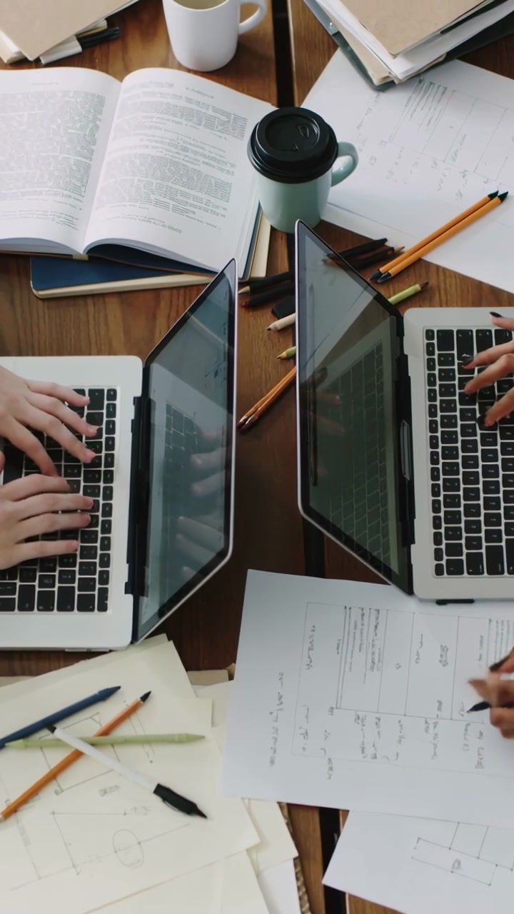 Vertical video: Typing two people working after shot start, writing at wooden table with laptops