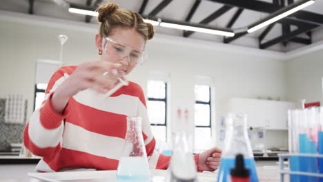 Conducting science experiment in school, young girl wearing safety goggles, focused on task