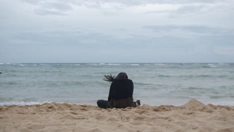 the back of a woman with mental illness seeks solace at the beach - static shot