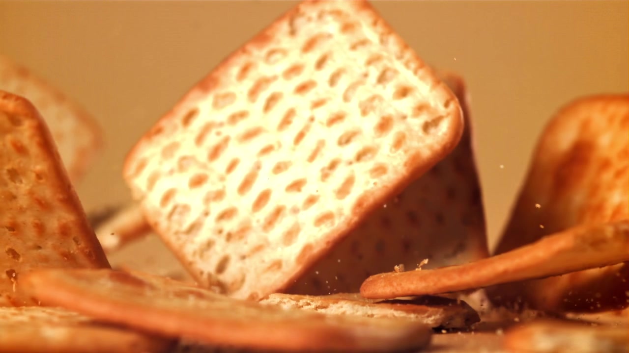 Golden Square Crackers Falling and Breaking in Slow Motion