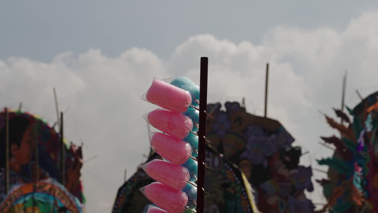 Bags of pink and blue cotton candy hang beside giant colorful kites in Sumpango Guatemala