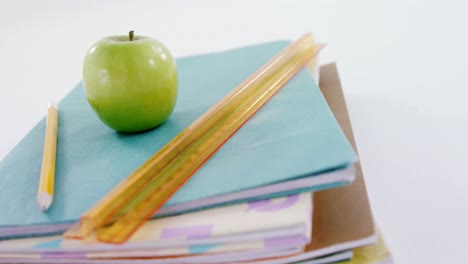 manzana, lápiz y regla de escala en una pila de libros