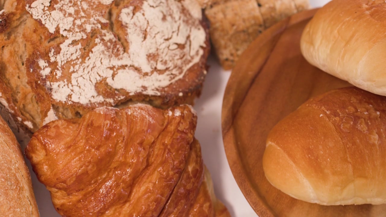 Assortment of Freshly Baked Bread and Pastries on a Wooden Plate