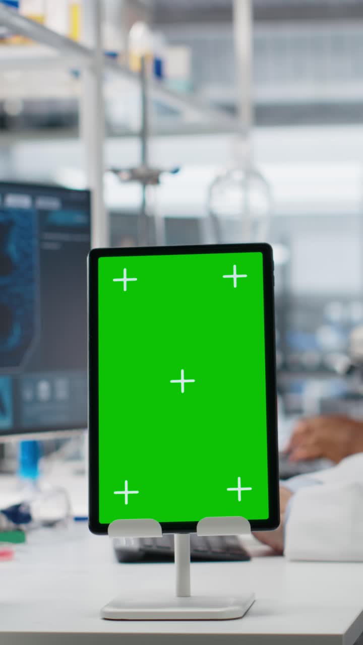 Vertical video Lab expert at desk using green screen tablet, looking at molecular model