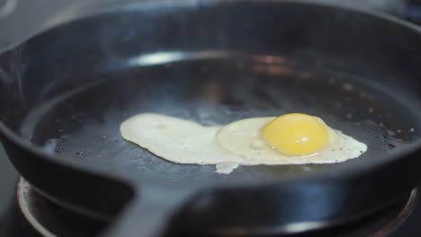 Raw-egg-falling-into-hot-cast-iron-skillet