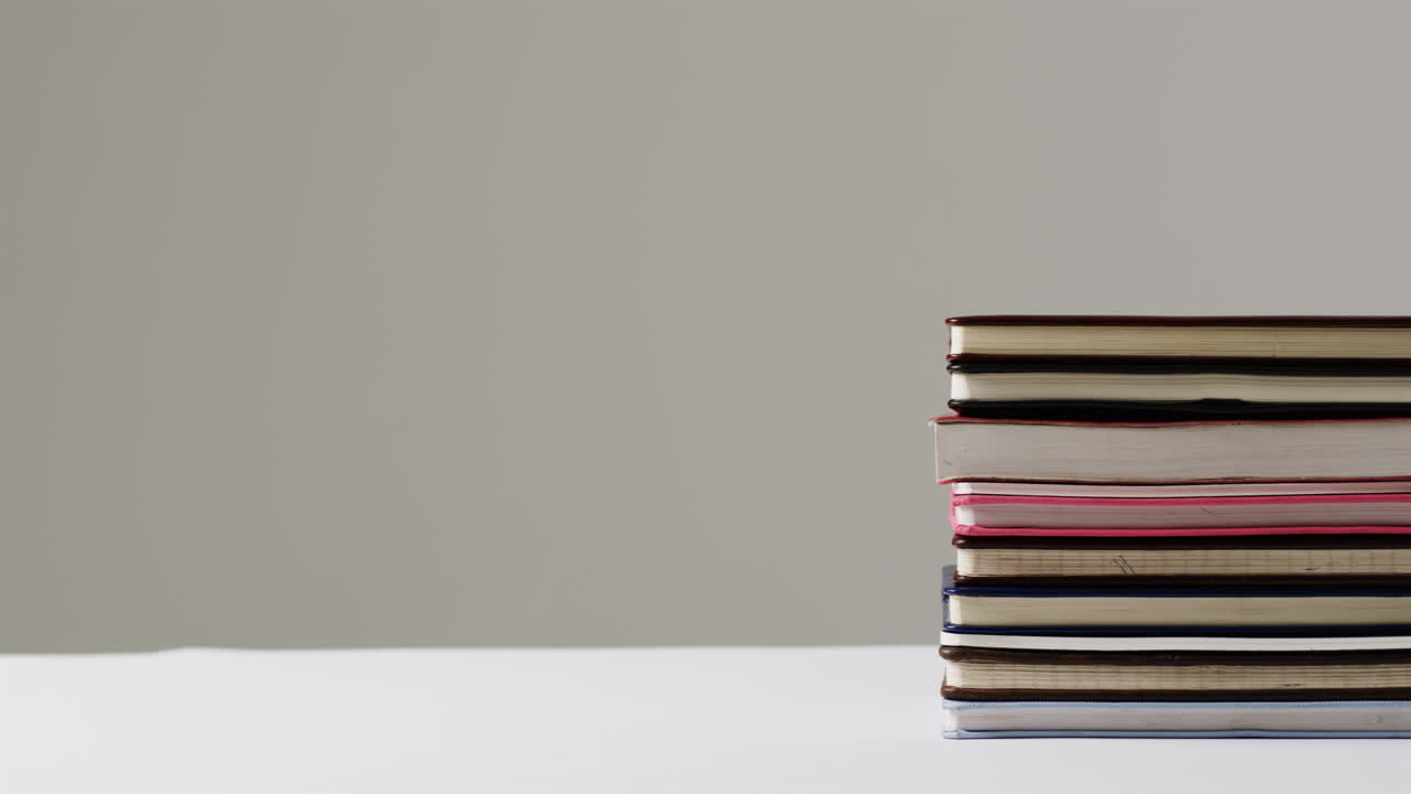 A stack of variously sized books sits on a white surface
