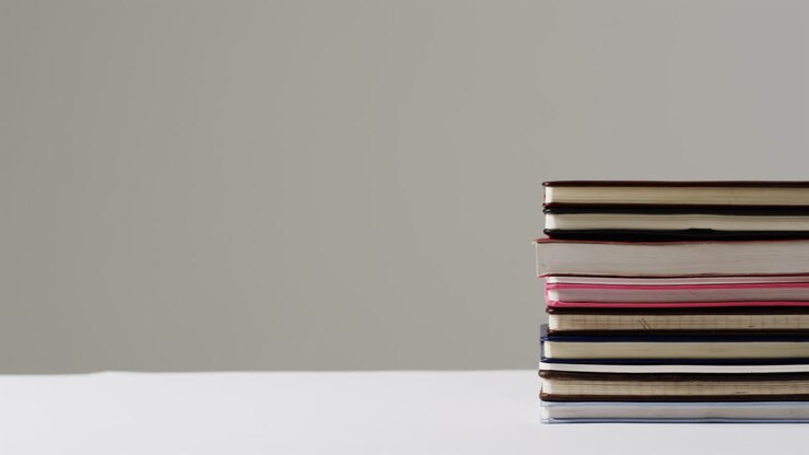 Una pila di libri di varie dimensioni su una superficie bianca