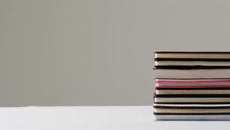 A-stack-of-variously-sized-books-sits-on-a-white-surface