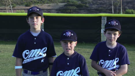 jóvenes jugadores de béisbol cruzan los brazos y posan