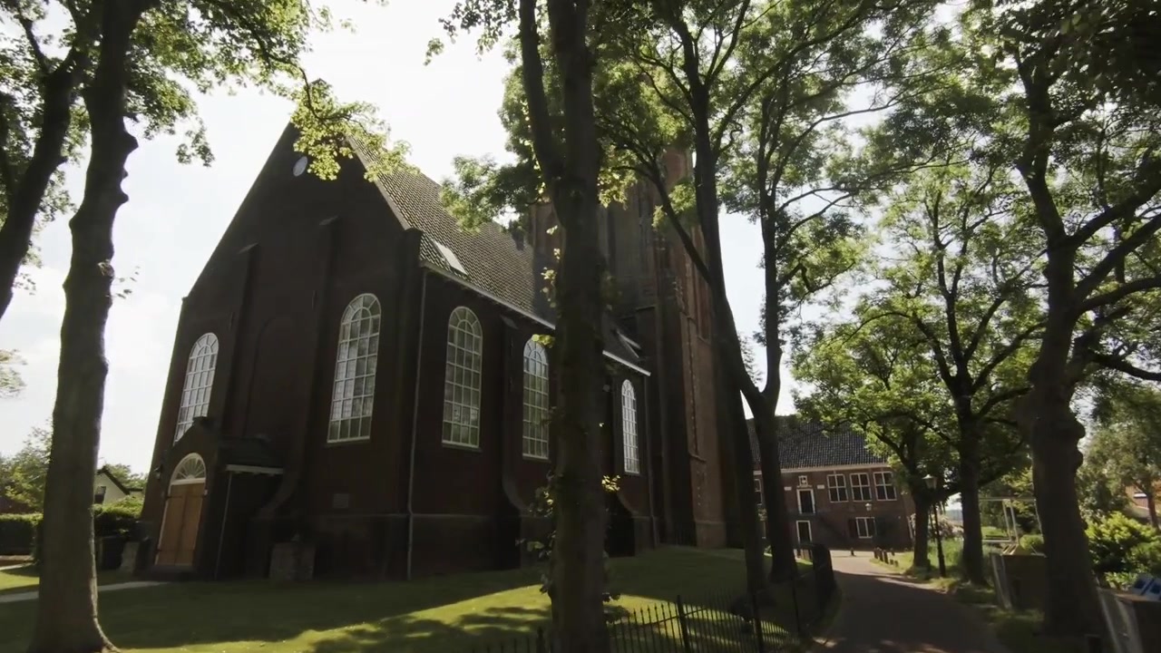 Fremadgående kamerakørsel af en smuk kirke omgivet af træer i Ransdorp, nær Amsterdam, Holland.