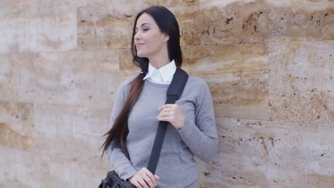 grinning woman in sweater near wall looking over