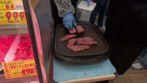 person cooking meat on a hotplate outdoors.