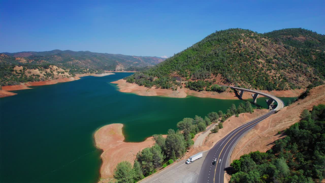 미국 캘리포니아에 있는 호수 위의 다리를 건너는 자동차의 공중 드론 샷
