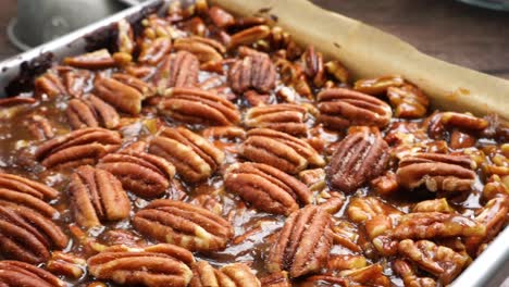 baking delicious caramel pecan brownies. panning across the baking pan with caramel pecan brownies. freshly baked gooey chocolate brownies with sweet caramel and nutty pecans.