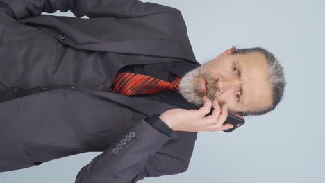 ⁇ 은 사업가가 전화로 이야기하는 동안 방해를 받고 화를 내는 수직 비디오.