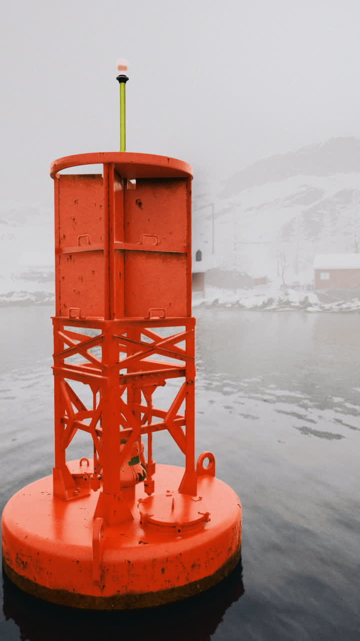 Bright orange buoy floats in tranquil waters of a foggy fjord landscape