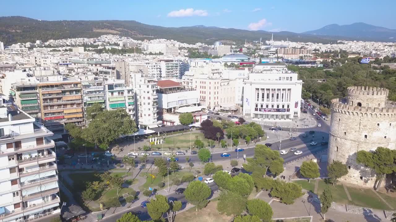 la torre blanca de tesalónica frente al teatro nacional del norte de grecia y el edificio del teatro de aristóteles con vehículos en la carretera - drone aéreo
