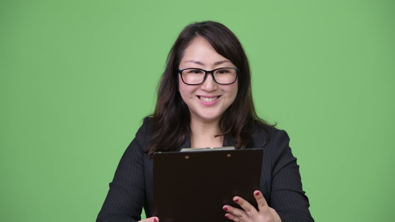 성숙하고 아름다운 아시아 사업가 여성이 클립보드를 읽습니다.