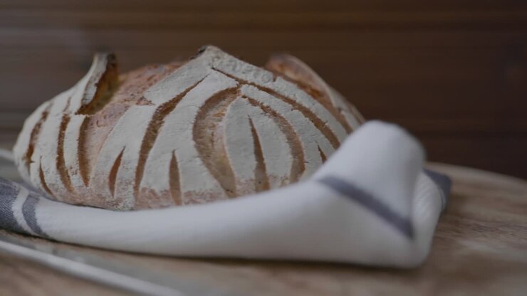 A fresh baked loaf of artisan sourdough bread rotating on a wooden platform
