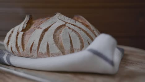 a fresh baked loaf of artisan sourdough bread rotating on a wooden platform