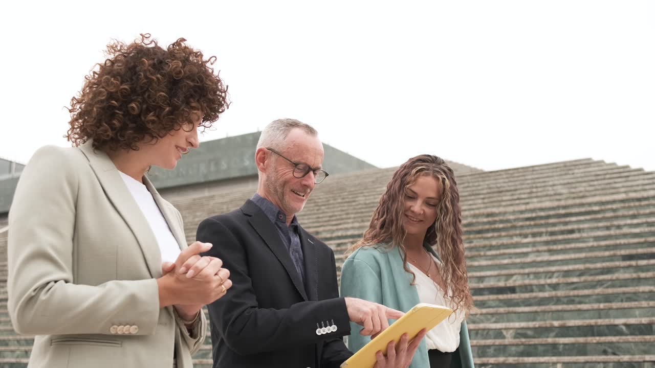 Happy business people using tablet near steps in city