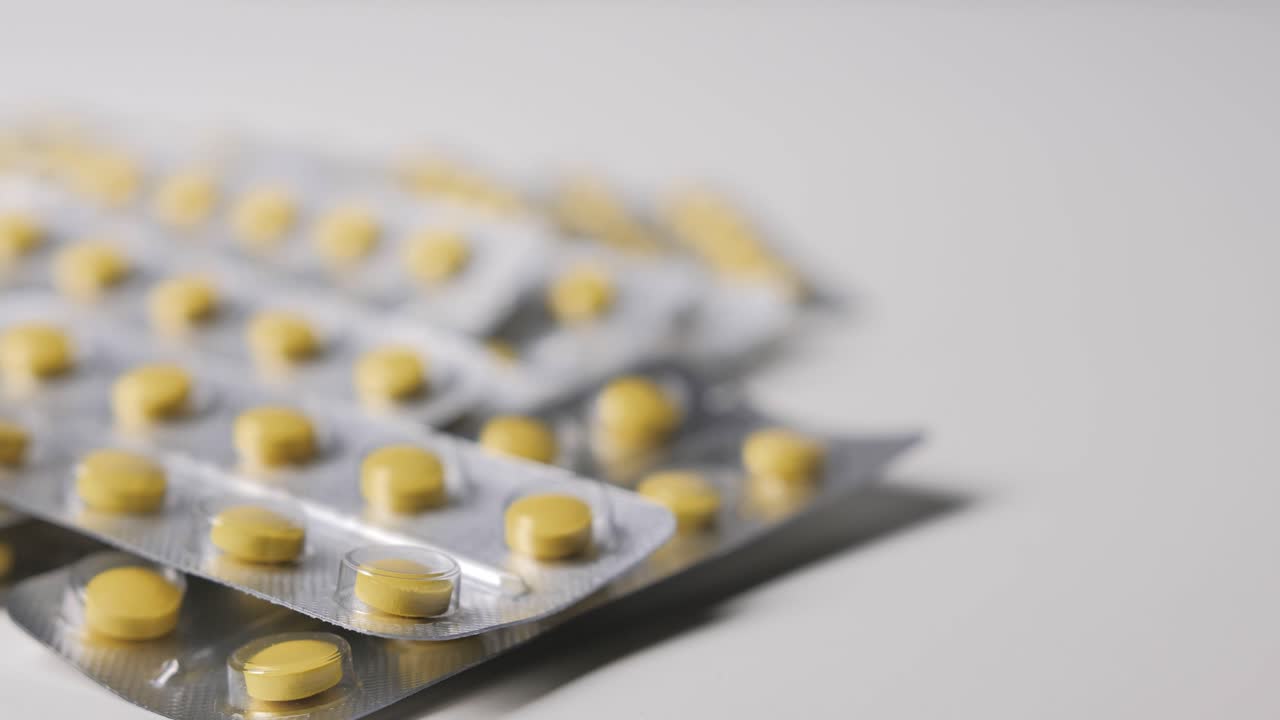 Yellow pills with packages on white background. Follow focus.