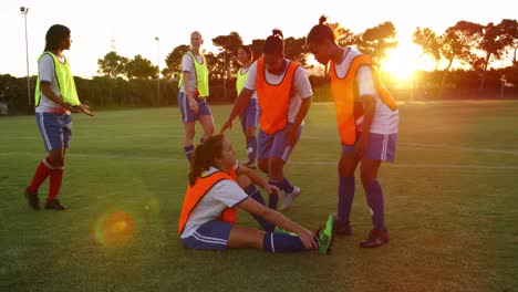 female soccer player helping teammate to stand on soccer field. 4k