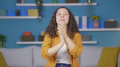una mujer joven aplaudiendo emocionada a la cámara.
