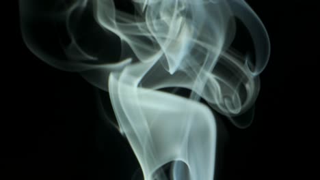 thin trickle silvery smoke slowly rising graceful twists upward. cigar smoke blowing from bottom to top. close-up, isolated on black background