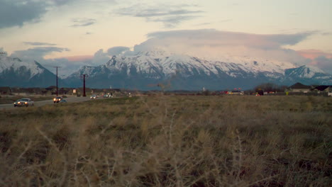 view of the snow-capped mountains in early morning or evening from between two highway roads - sliding shot