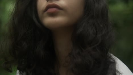 자연으로 둘러싸인 숲의 중심에 위치한 검은 머리카락의 외로운 그리고 사려 깊은 여성의 클로즈업 뷰
