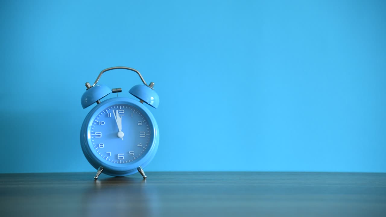 나무 테이블에 있는 파란 알람 시계의 시간 지연