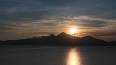 Timelapse-De-Día-A-Noche-De-Una-Puesta-De-Sol-En-Vietnam-Sobre-Una-Bahía-Y-Una-Cordillera-Con-Barcos-Que-Pasan