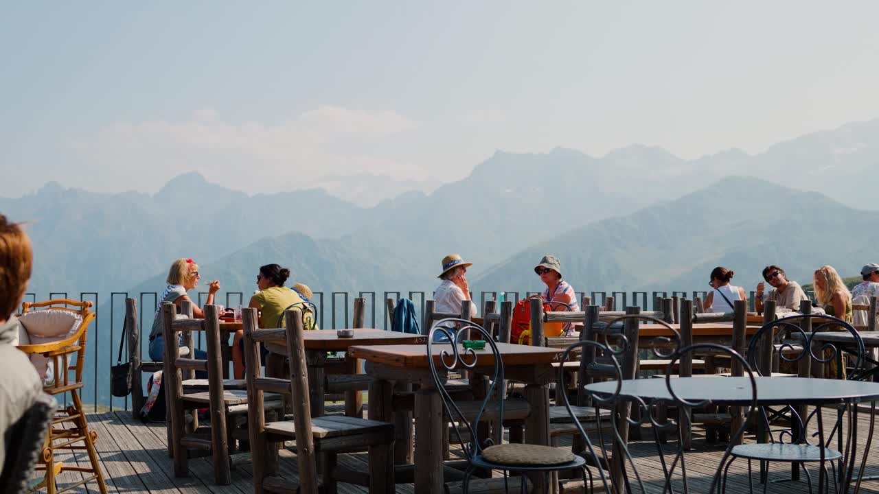 Mountain-view terrace with people dining outdoors in Luchon, France, on a sunny day