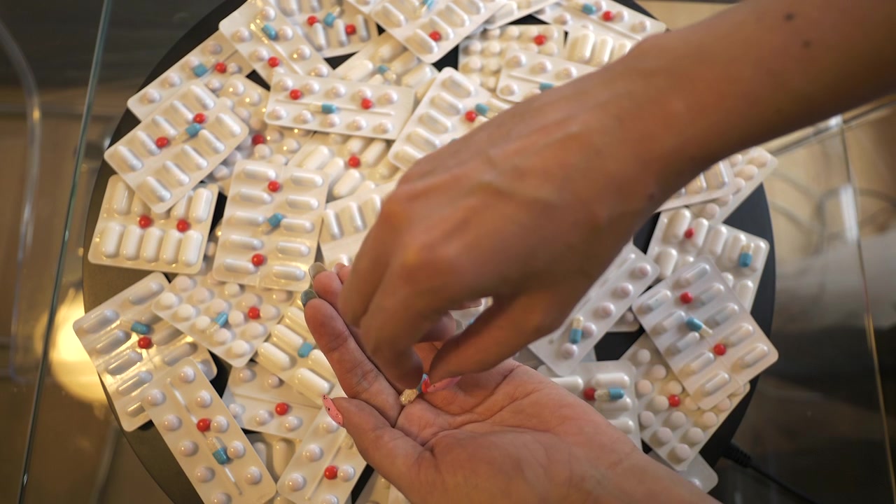 Person Collecting Various Medication Pills from Blister Packs