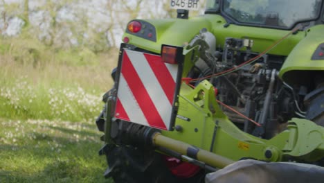 tractor using dual rotary swath windrower cutting grass