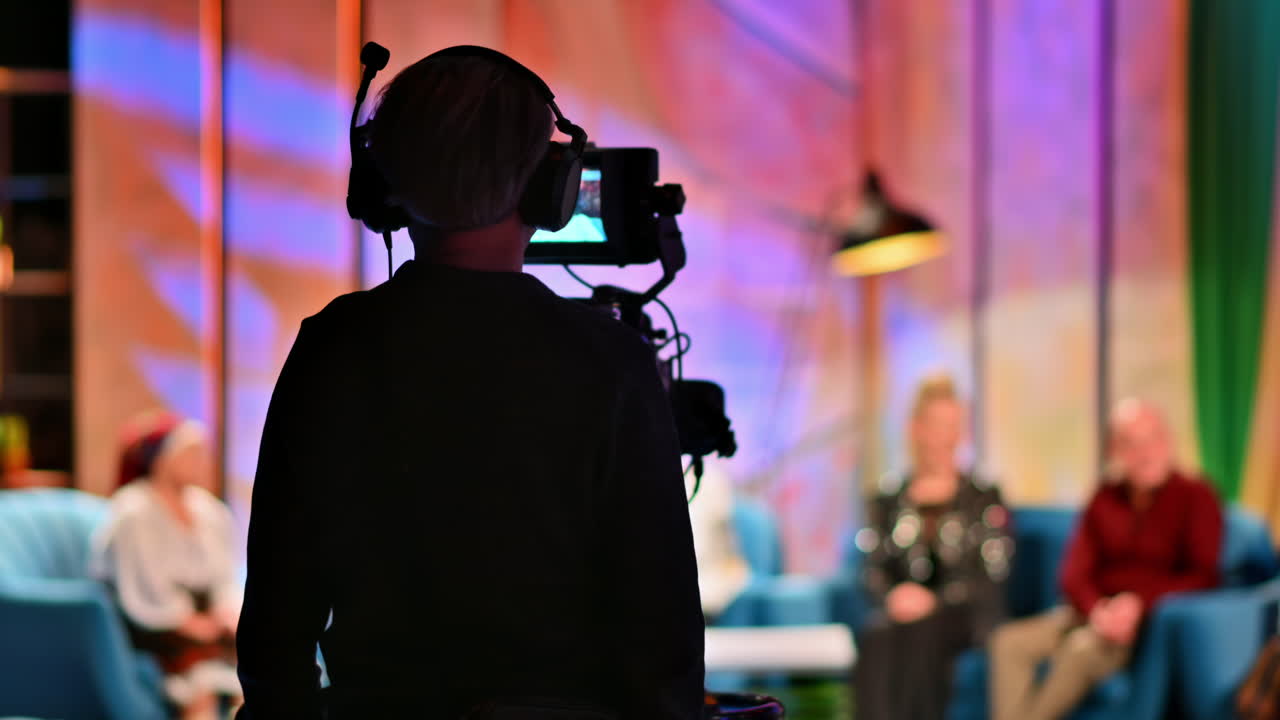 Cameraman filming a television talk show on a professional camera. Video production backstage in a dark studio