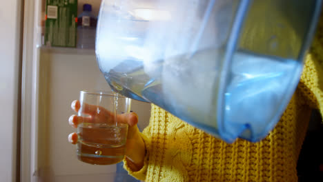 mujer vertiendo agua en un vaso en la cocina 4k