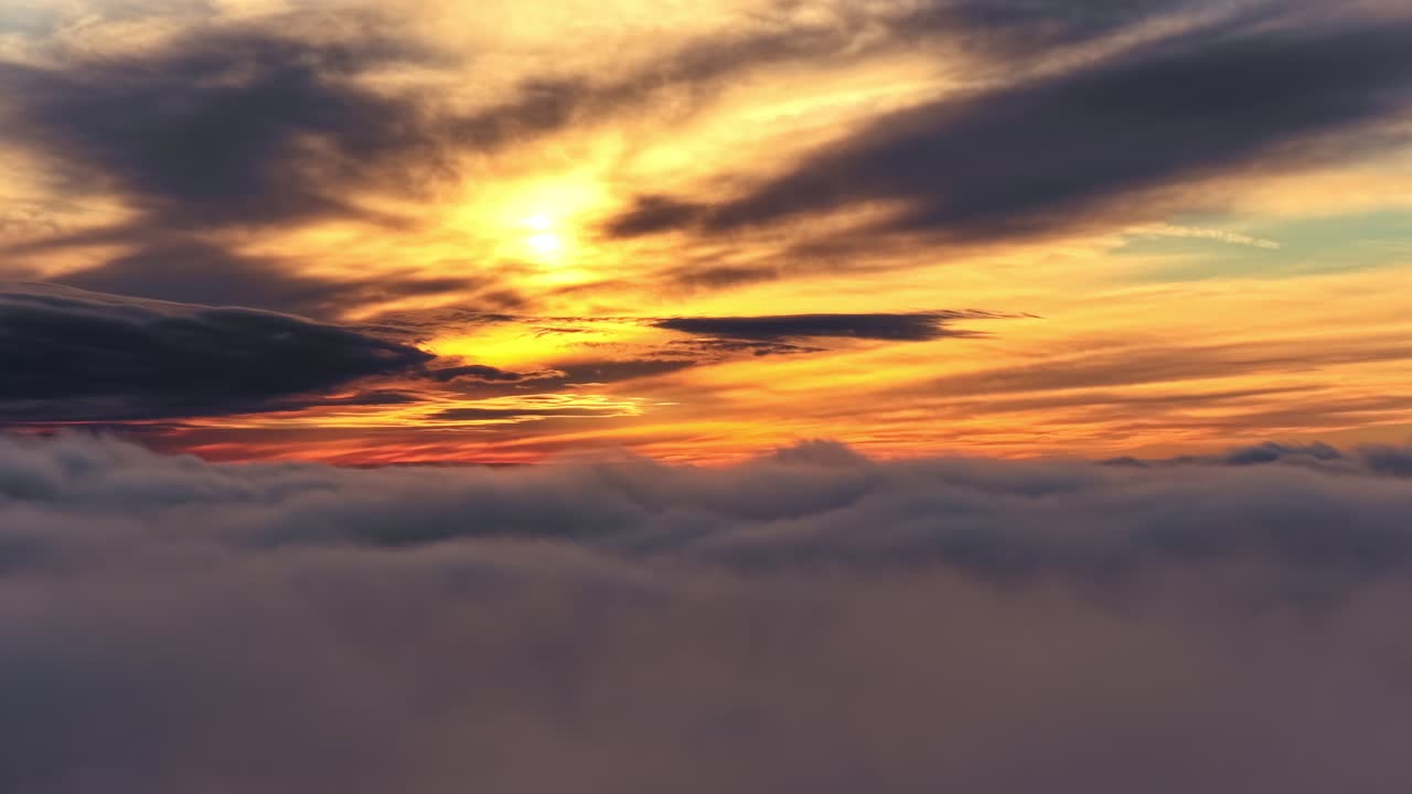 Drone above sunset sky ocean horizon with golden light and soft clouds reflecting on water