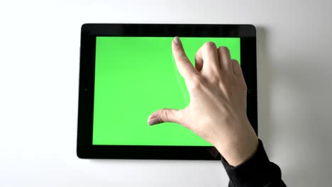 female hand doing pinch to zoom on tablet. green screen, chromakey concept, top shot 60 fps