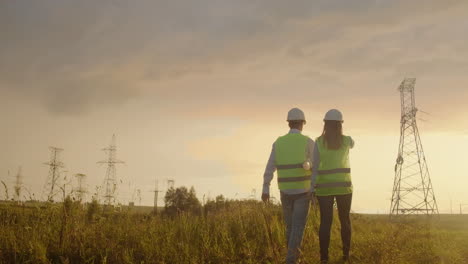 back two the engineer and the controller with a tablet pc and the drawings are about lines and transmission towers and discuss the expansion plan and transportation energy for towns and cities.