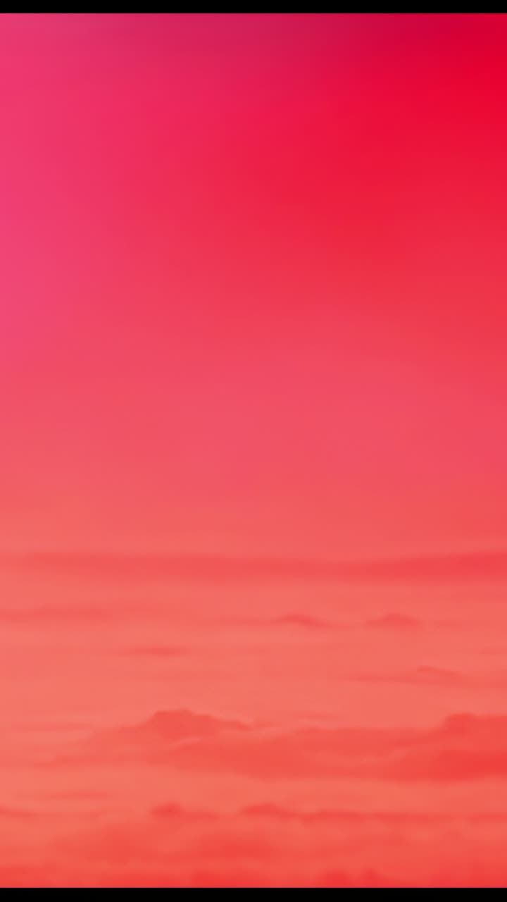 Vertical video: Cycling horizon shifting from yellow through red and back over water, color loop